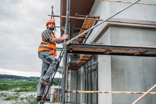 Construction workers climbing up a scaffold