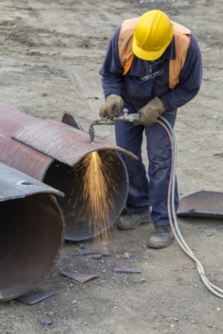 Worker Cutting Metal Pipes with Torch