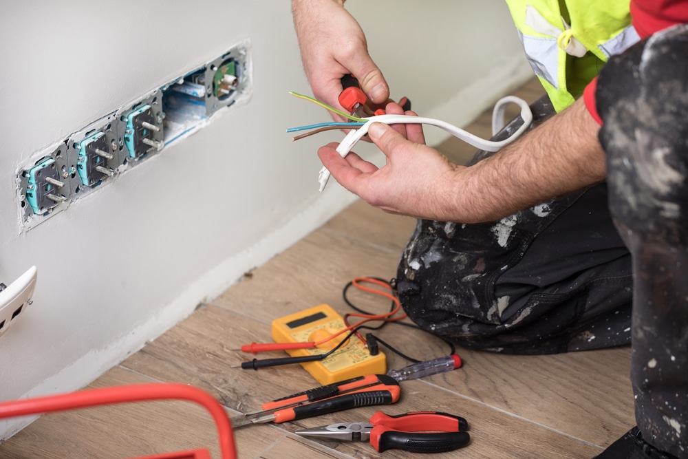 An electrician is working on an electrical outlet.