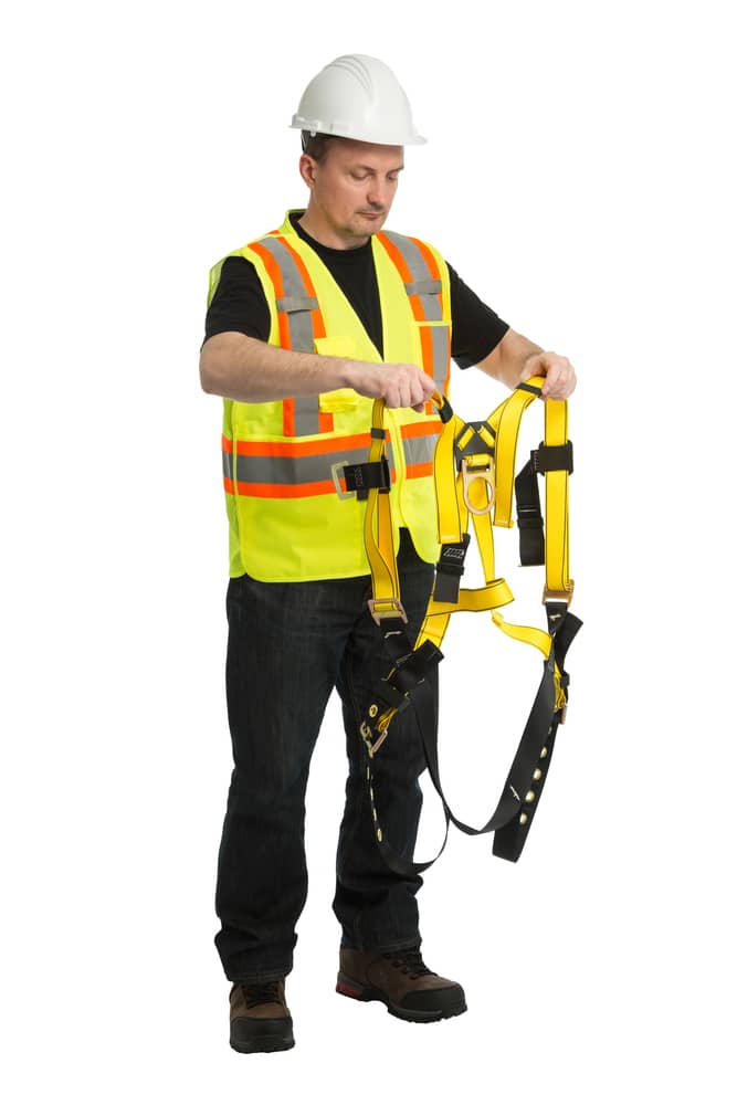 A man in a yellow vest holding a safety harness.