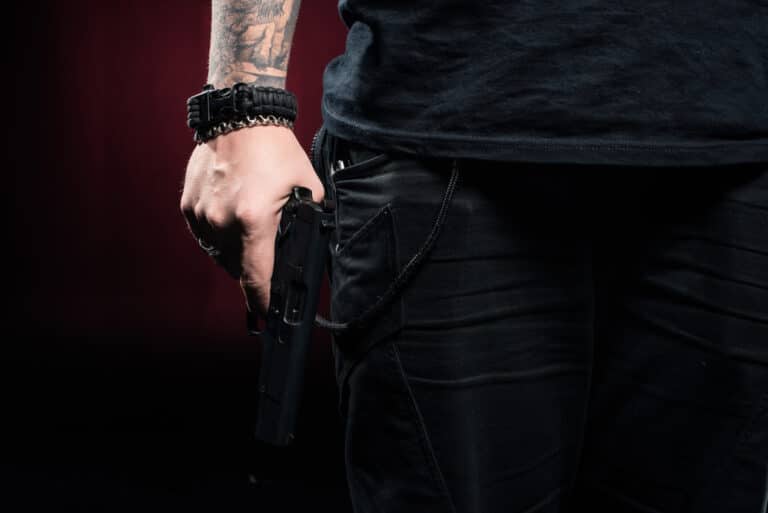 A man with tattoos holding a gun.