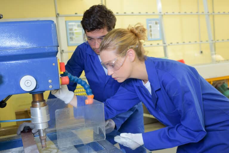 A man and a woman working on a machine.