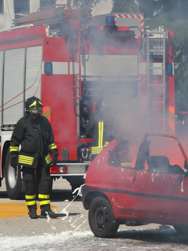 A firefighter standing next to a car.
