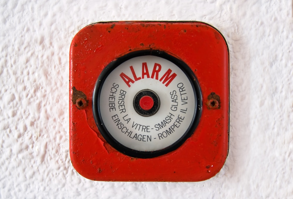 A red fire alarm on a white wall.