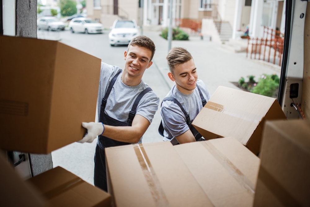 Two men loading boxes into a moving truck.