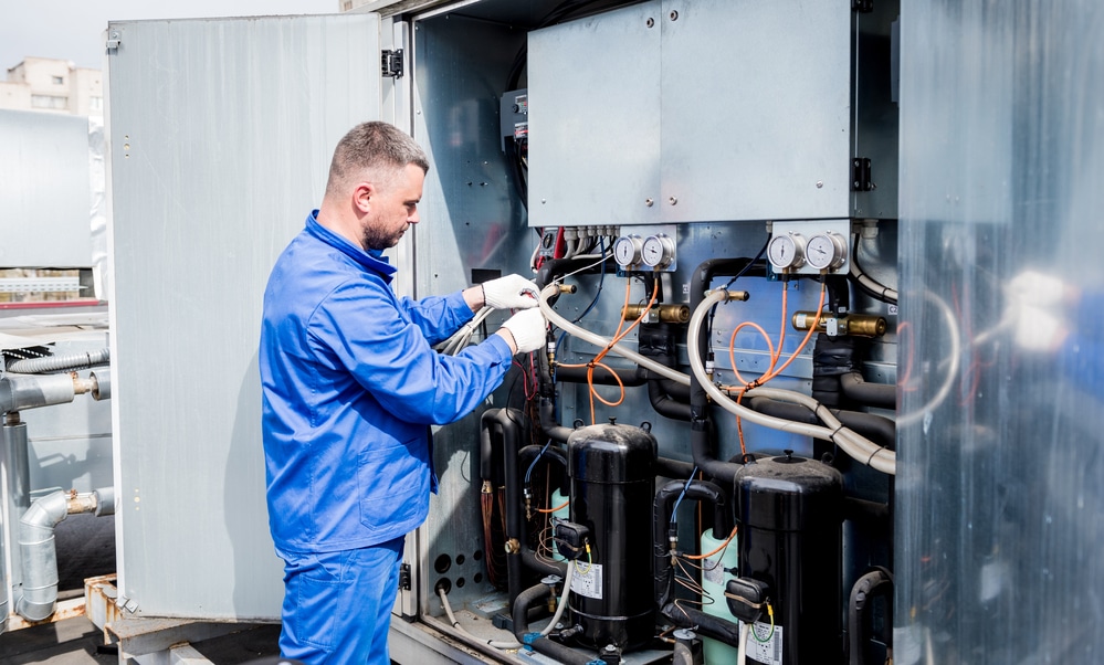 A man working on an air conditioning unit with safety sensors on it.