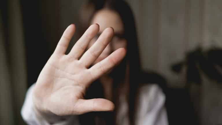 A woman is showing her hand in front of her face.