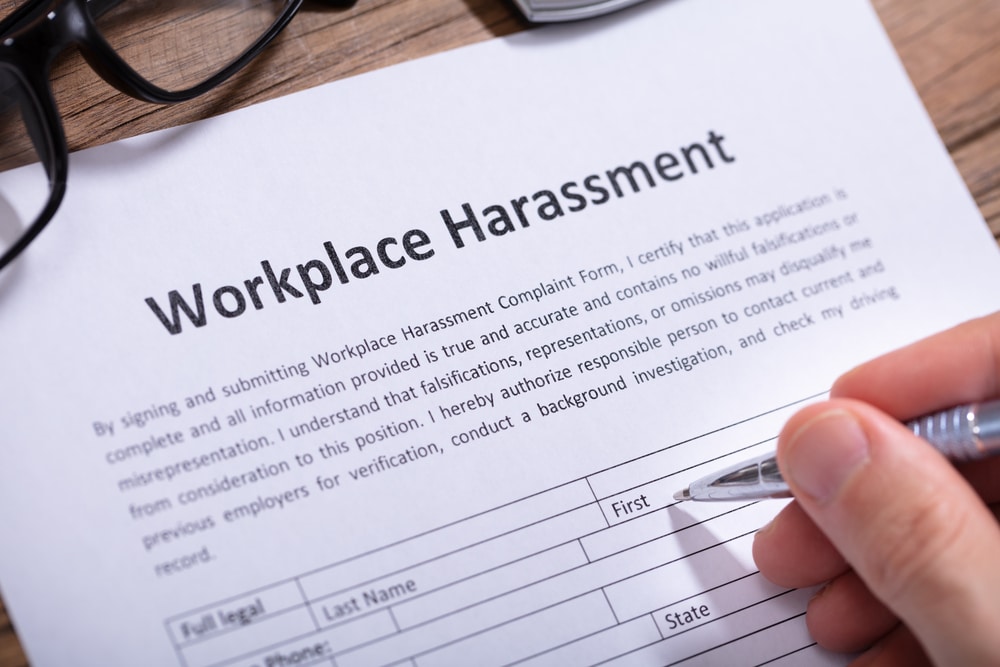 A person signing a document that says workplace harassment.