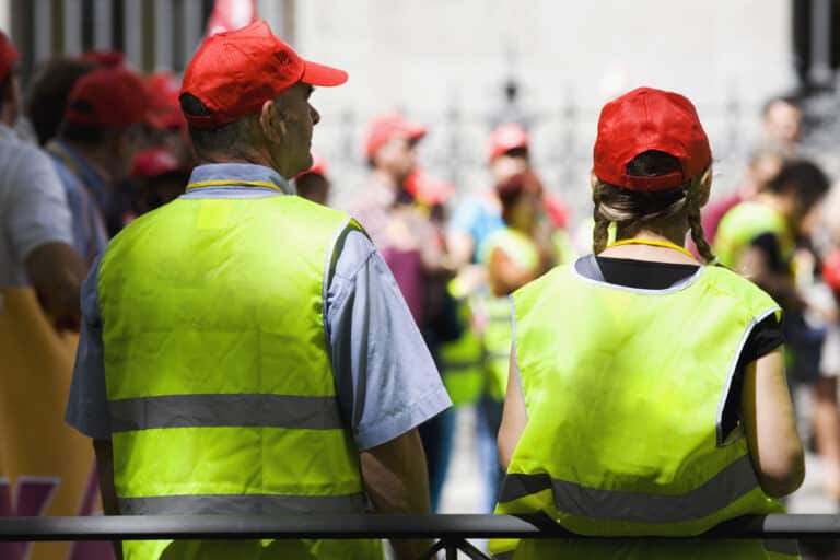 A group of people wearing yellow vests and red hats participating in an evacuation emergency drill