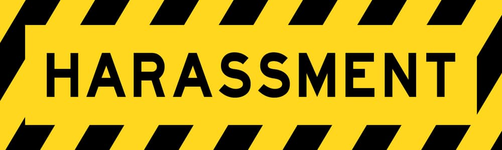 A yellow and black sign with the word harassment.
