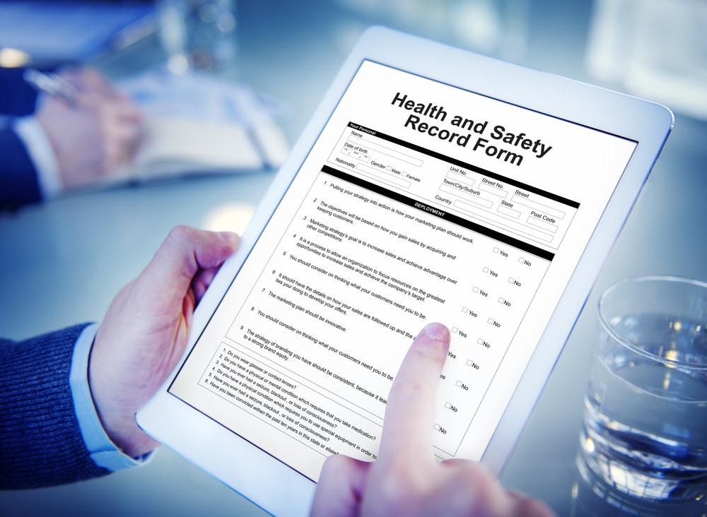 A person holding a tablet with a home and safety risk assessment form.
