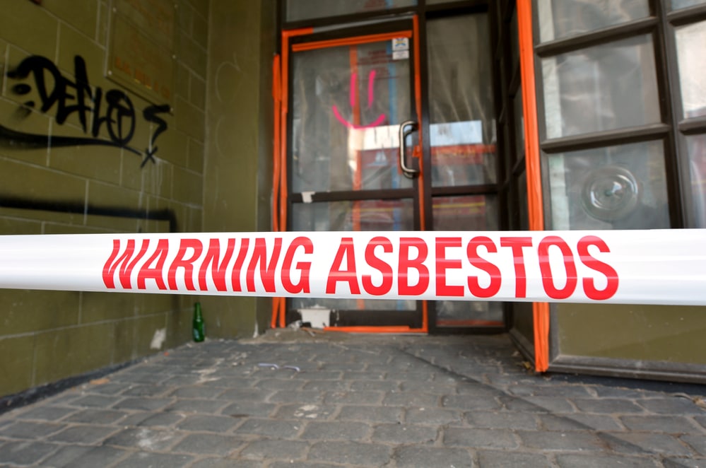 A warning sign for asbestos in front of a building.