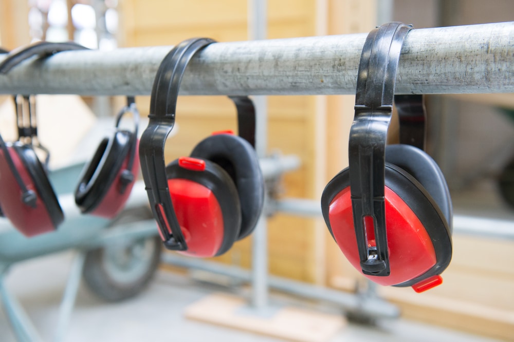 Several pairs of ear muffs hanging on a metal rod.