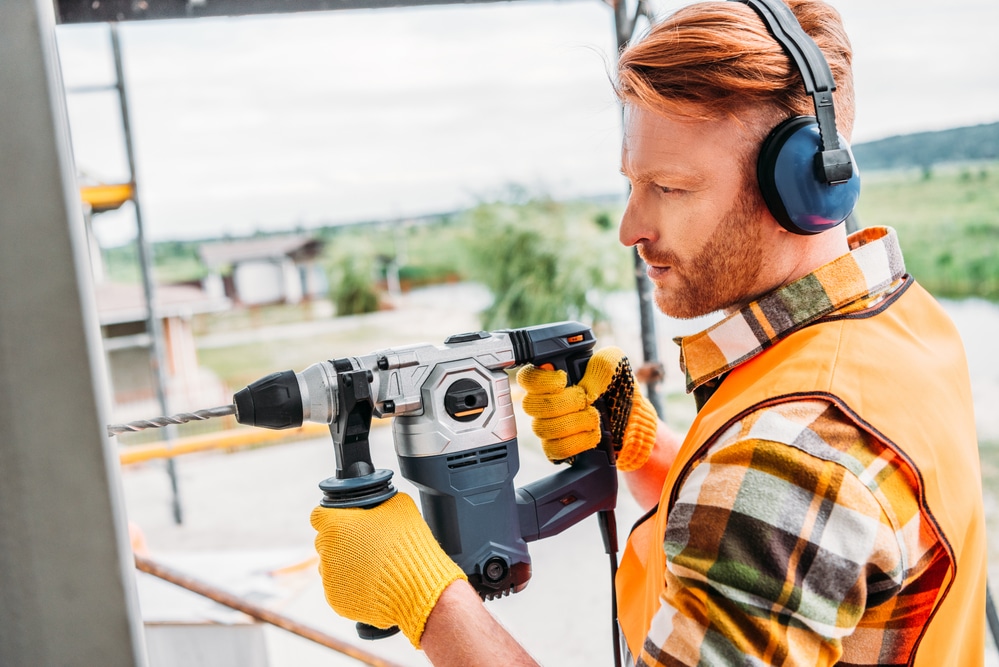 A construction worker using a hammer drill.