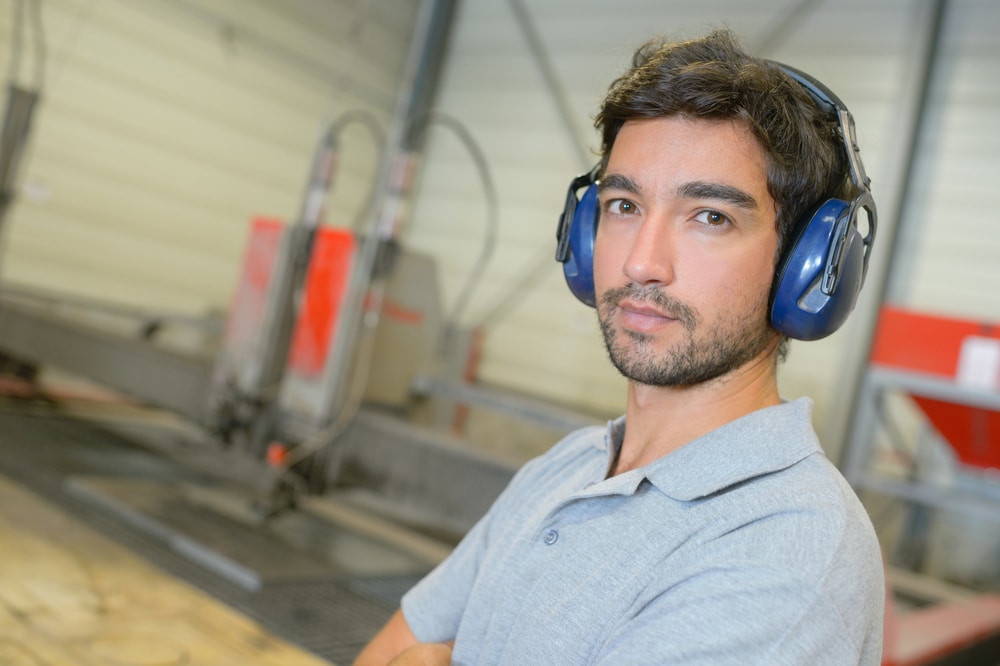 A man wearing ear defenders in a factory.