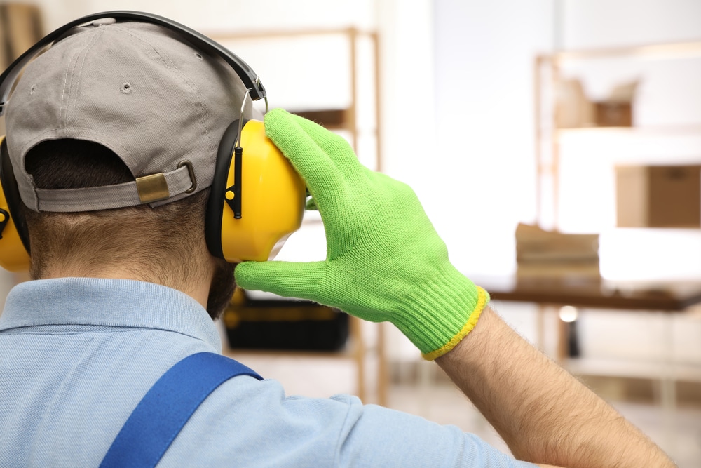 A worker wearing ear muffs in a warehouse.