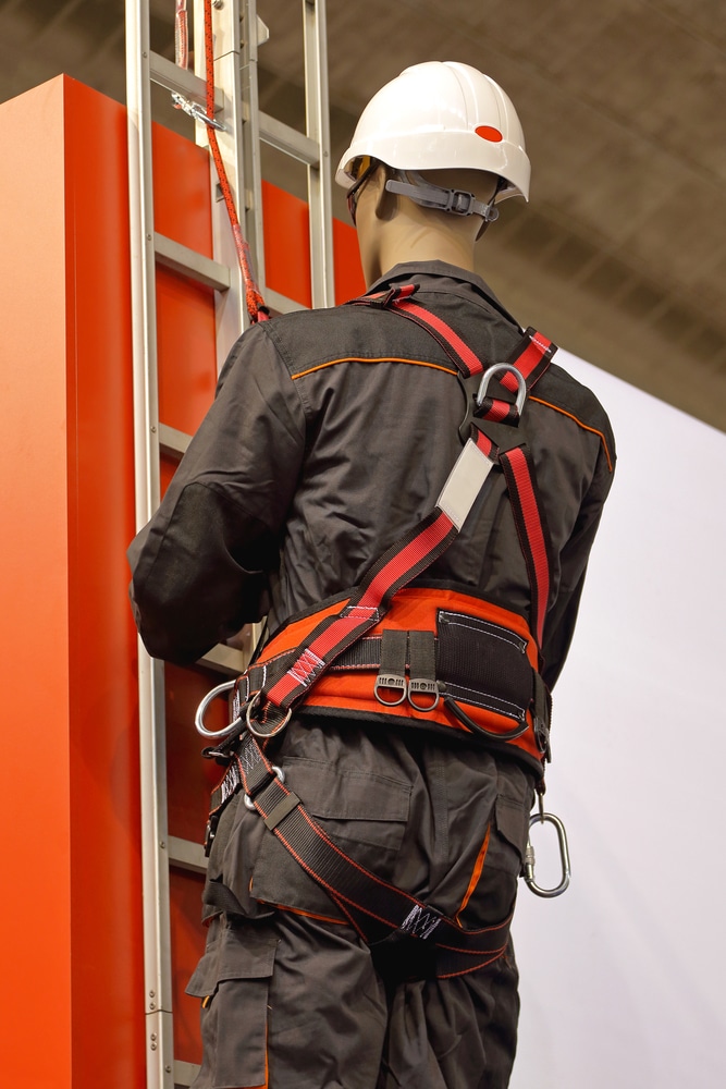 A man on a ladder wearing a safety harness for fall protection