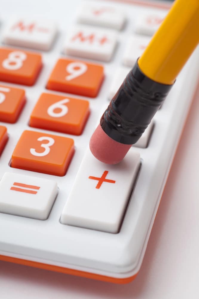 An orange and white calculator with a pencil on it.