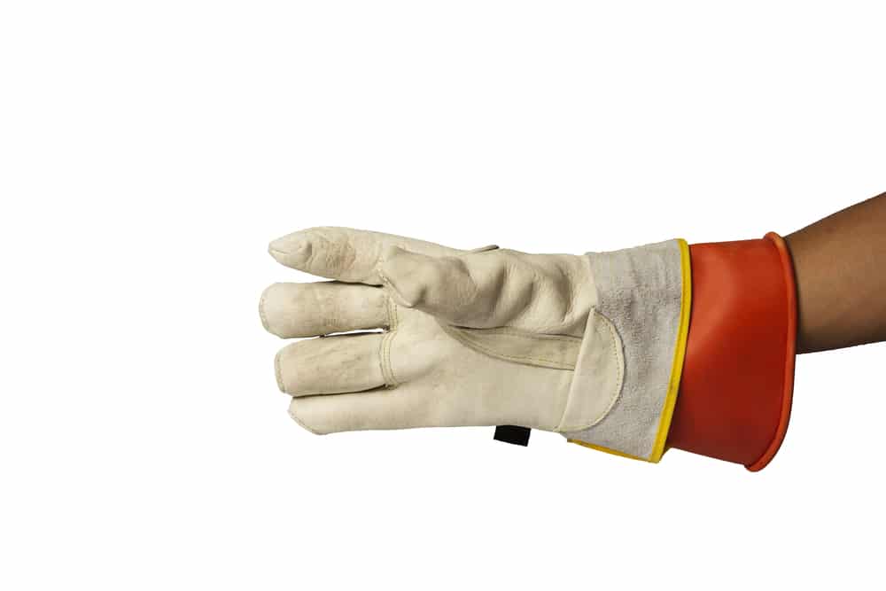 A close-up image of a human hand wearing a lineman's glove against a white background. The glove is made of cream-colored leather with a distinctive red cuff featuring a high-visibility yellow stripe. The robust construction suggests it is designed for electrical work, providing safety and insulation for the wearer.