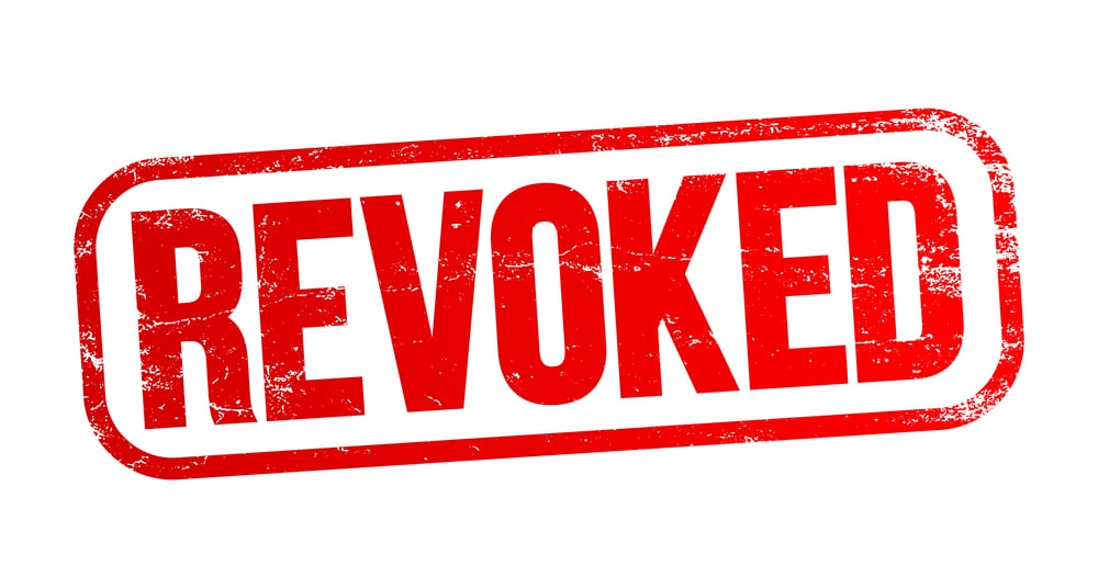 A distressed, red rubber stamp-style graphic with the word 'REVOKED' in bold, white capital letters. The design features a textured, grunge effect, indicating wear and usage, set against a plain background.
